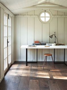 an image of a room with wood floors and white paneling on the walls, along with a small table