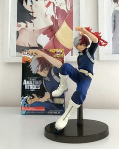 a figurine sitting on top of a table next to a book and poster