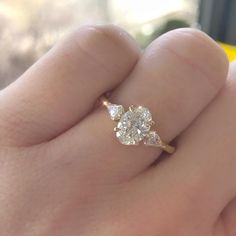 a close up of a person's hand holding a diamond ring