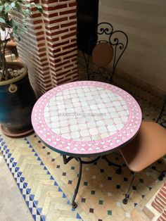 a table and chair sitting in front of a brick wall with a potted plant