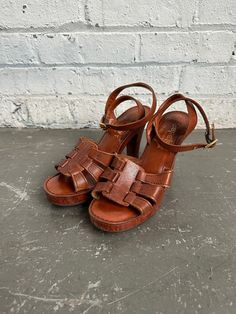 These 1970s Capeto's platform sandals are a MUST for anyone looking to add a timeless vintage staple to their shoe collection. Shoes are made of supple leather with plenty of wear left in them. Platform and heel are wood & ankle clasps have been recently replaced--buckles may be a little stiff but should loosen up as they are used with the leather strap holes over time. Made in Brazil! Labeled a Women's Size 6.5 In great vintage condition--heels have some slight wear & tear but nothing major! MEASUREMENTS: Heel height: 4 inches Platform height: .75 inches Vintage Sandals 1980, Retro Sandals With Buckle Closure, Retro Sandals With Buckle Closure And Round Toe, Retro Round Toe Sandals With Buckle Closure, Vintage Sandals With Block Heel For Spring, Vintage Block Heel Sandals For Spring, Vintage Stacked Heel Summer Heels, Retro Leather Open Toe Sandals, Vintage Open Heel Wedge Sandals For Summer