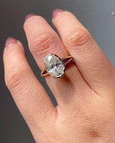 a woman's hand with a diamond ring on top of her finger and the other hand holding an engagement ring