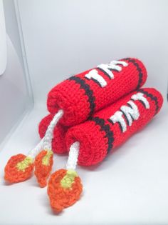 two crocheted hotdogs on top of each other with carrots attached to them