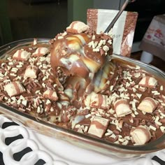 there is a chocolate dessert with nuts on top and ice cream drizzled over it