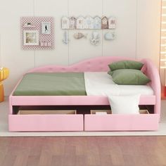 a pink bed with drawers underneath it in a room that has white walls and wooden floors