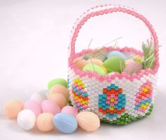 a basket filled with lots of colorful eggs next to some candy candies on a white surface