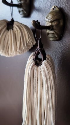 two white tassels hanging from hooks on a wall