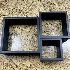 three black square trays sitting on top of a marble counter next to each other