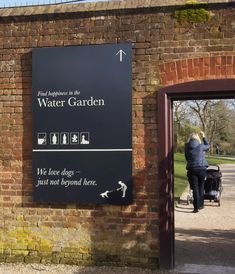 a sign on the side of a brick building that says water garden, we love dogs just not beyond here