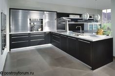 a modern kitchen with black cabinets and white counter tops, stainless steel appliances and an island in the middle