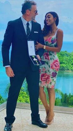 a man in a suit and tie standing next to a woman wearing a floral dress