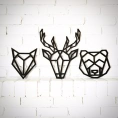 three metal deer head sculptures on a white brick wall