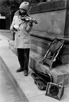 a man is playing violin on the sidewalk