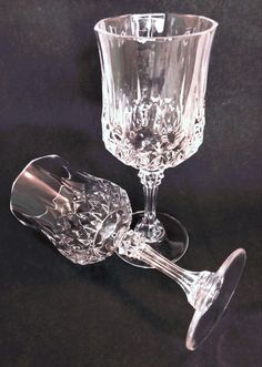 two crystal goblets sitting next to each other on a black tableclothed surface