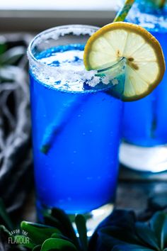 two glasses filled with blue liquid and lemon wedges