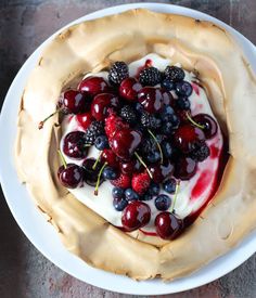 three small pies with berries and whipped cream on them sitting on a yellow and white plate