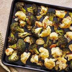 roasted cauliflower and broccoli on a baking sheet with a cloth next to it