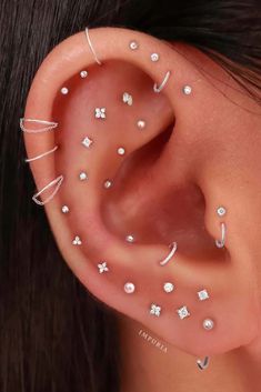 a woman's ear with multiple piercings on the top and bottom of it