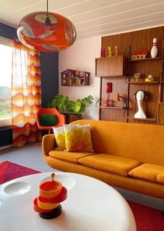 a living room with an orange couch and white coffee table in front of a window