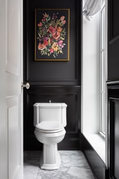 a white toilet sitting in a bathroom next to a painting on the wall above it