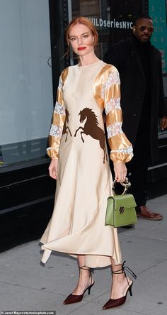 a woman in a dress and heels is walking down the street with her handbag