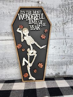 a skeleton is standing in front of a wooden sign that says it's the most wonderful time of year