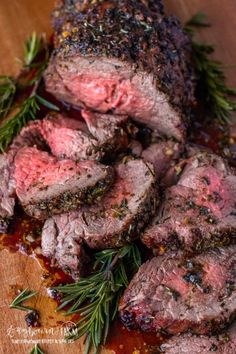 some meat is sitting on a cutting board with rosemary sprigs and seasoning