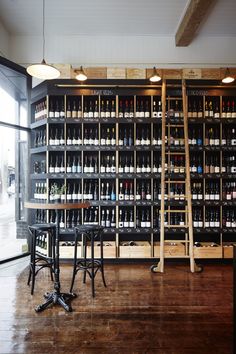 two stools sit in front of a wall full of wine bottles