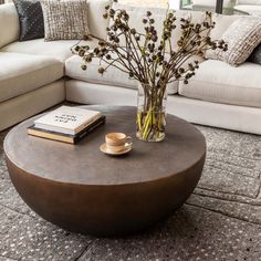 a coffee table with flowers in a vase on it and a book next to it