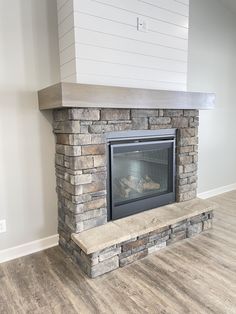 a fireplace with a stone mantle and white shiping on the top shelf in a living room