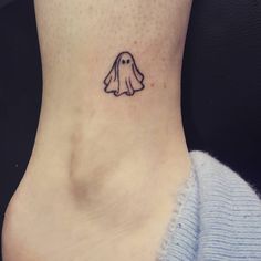 a small ghost tattoo on the back of a woman's neck and ankle area