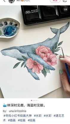 someone is drawing with watercolors on paper and using a brush to paint the whale