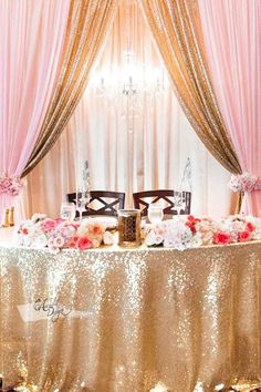 the table is set with pink flowers and gold sequins for a wedding reception