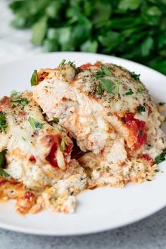 a white plate topped with lasagna covered in cheese and sauce next to parsley