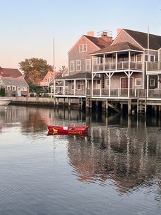 a red boat floating on top of a body of water next to tall wooden buildings