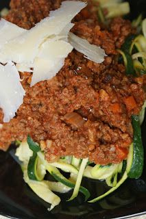 a black plate topped with zucchini and meat covered in grated parmesan cheese