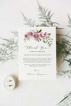 a wedding thank card with pink flowers and greenery on the side, next to a button