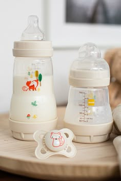 two baby bottles sitting on top of a wooden table