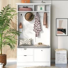 a white shelf with some hats on top of it and a potted plant next to it