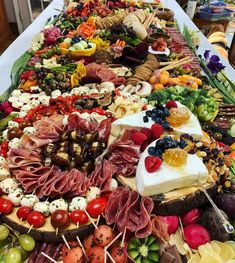 a long table covered with lots of different types of food on sticks and cheeses