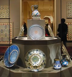 there are many plates and vases on display