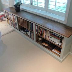 a bookshelf in the corner of a room with two windows and a couch