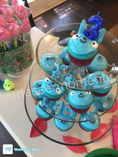 cupcakes with blue frosting and decorations on a glass platter in the shape of an elephant