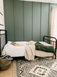 a bed with blankets on top of it next to a rug and wall hangings