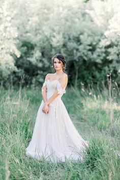 a woman in a white dress standing in tall grass