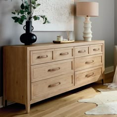 a large wooden dresser sitting next to a lamp on top of a hard wood floor