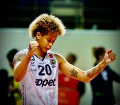 a male basketball player in a white uniform with tattoos on his arms and hands up