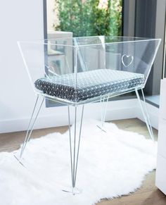 a clear chair sitting on top of a white rug in front of a glass window