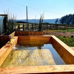 an outdoor hot tub in the middle of a field with water flowing out of it