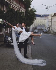 a bride and groom are posing on the street with their wedding dress blowing in the wind